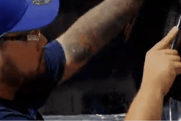 Technician wearing gloves using a squeegee tool to smooth window tint film during automotive installation.